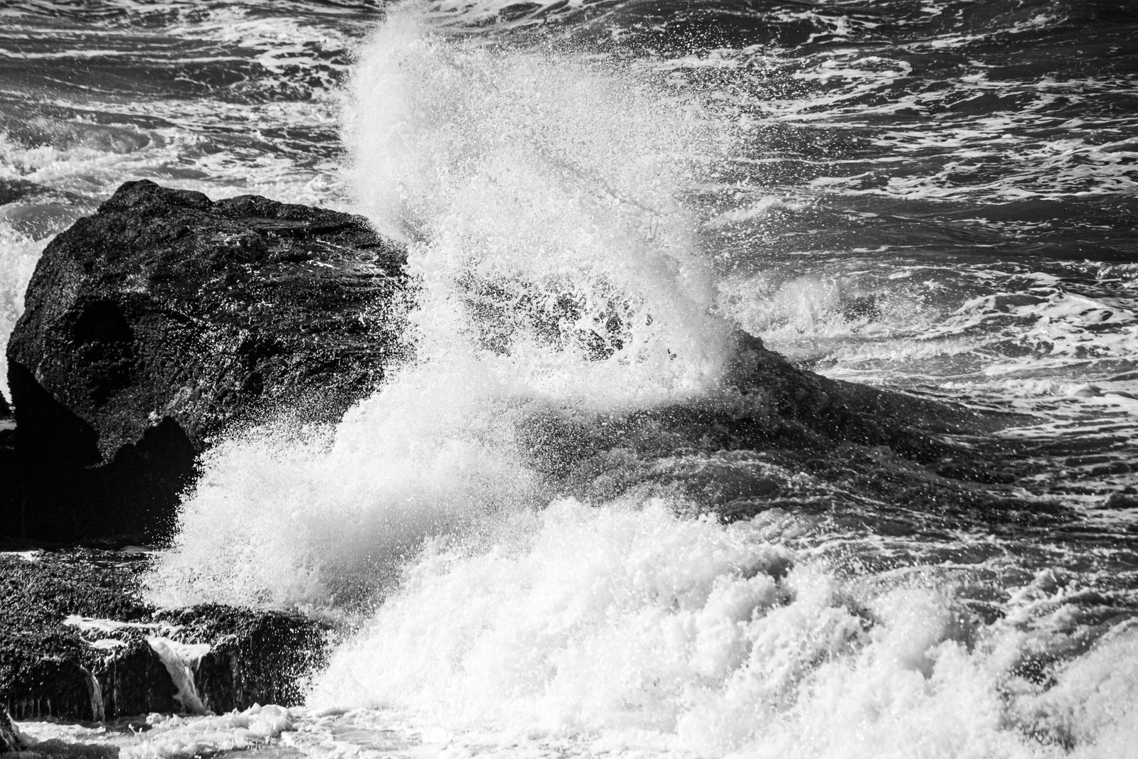 Captivating black and white shot of waves crashing against rocks in Mar del Plata, Argentina.