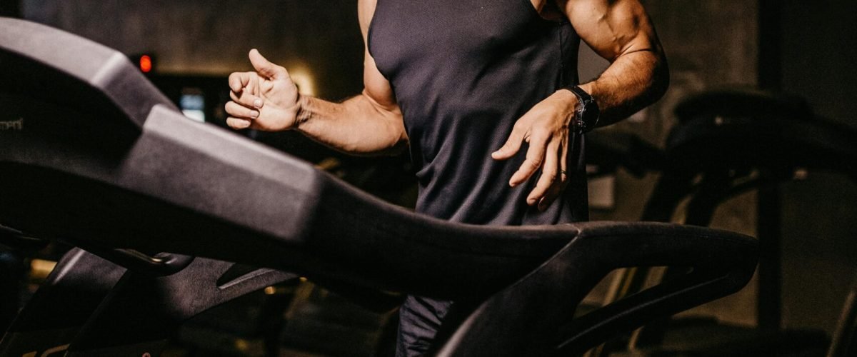 Focused man running on a treadmill in a gym, showcasing athleticism and fitness.